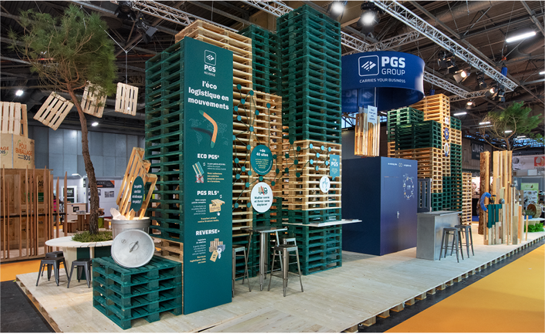 Mise en scène pile de palettes vertes et blanches avec un réseau de cordes vertes qui illustrent le maillage des sites PGS en France et à l’étranger - vue du stand de 100m2 conçu par Atribu pour PGS group, sur le salon all4pack 2022