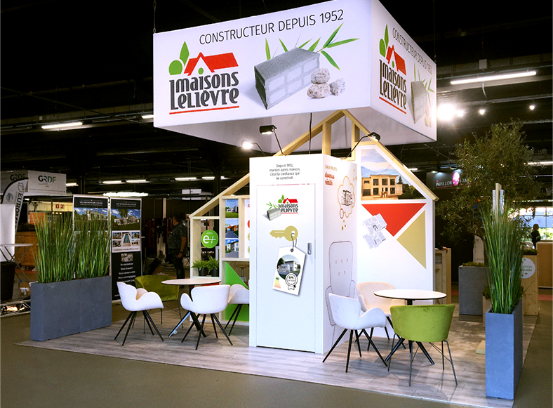 Vue de l’arrière du stand Maisons Lelièvre créé par Atribu - Architecture bois et deux pôles de réunion de part et d’autre d’une petite réserve